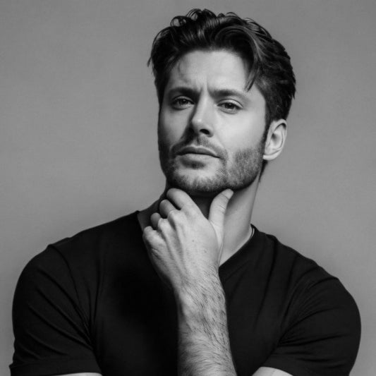 Black and white portrait of a man with his hand on his chin against a gray background